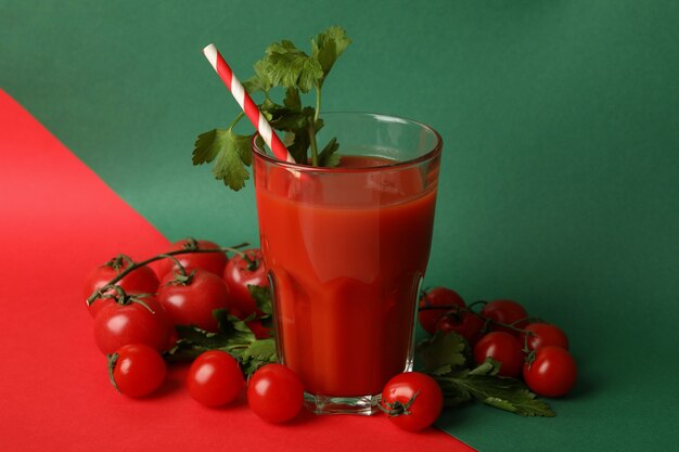 Glass of tomato juice and tomatoes on two tone background