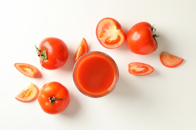 Glass of tomato juice and tomatoes on white