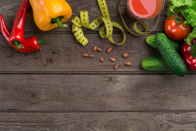 Glass of tomato juice with vegetables and measuring tape on wooden table close-up. Copy space. Top view