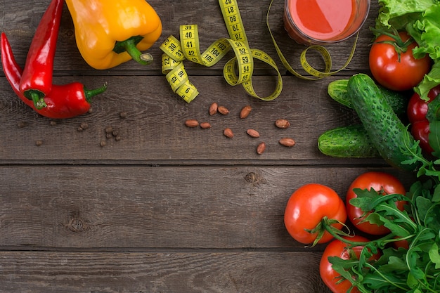 Glass of tomato juice with vegetables and measuring tape on wooden table close-up. Copy space. Top view