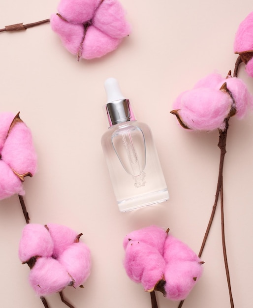 Glass transparent white bottle with a pipette Container for cosmetics acids and oils on a beige background top view