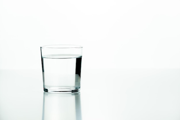 Glass tumbler filled with water on a white background with a minimalist concept and plenty of copy space