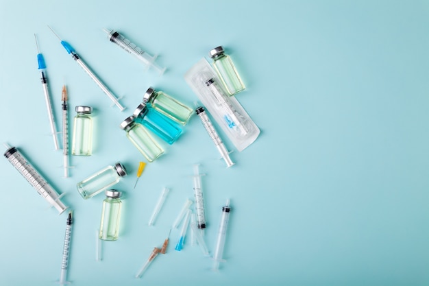 Glass vaccine ampoules bottles and syringes needles top view