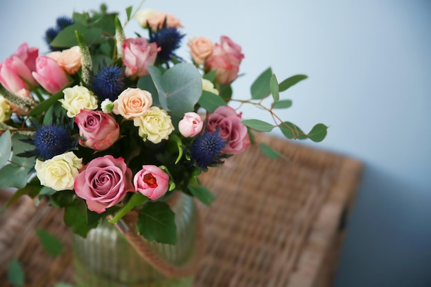 Glass vase with bouquet on blurred background