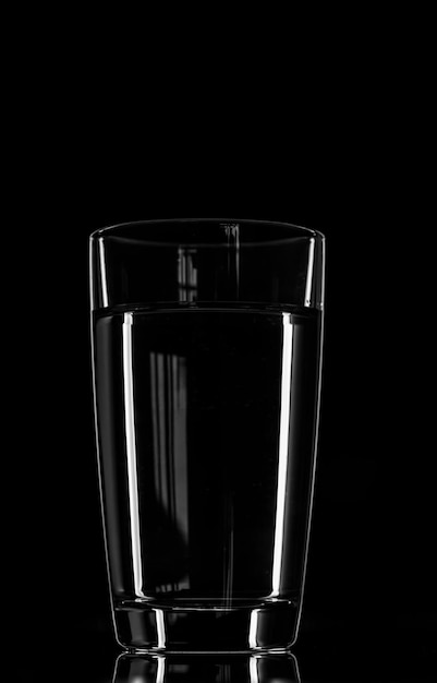 Glass of water on a black background. glare of light. minimalism, drink