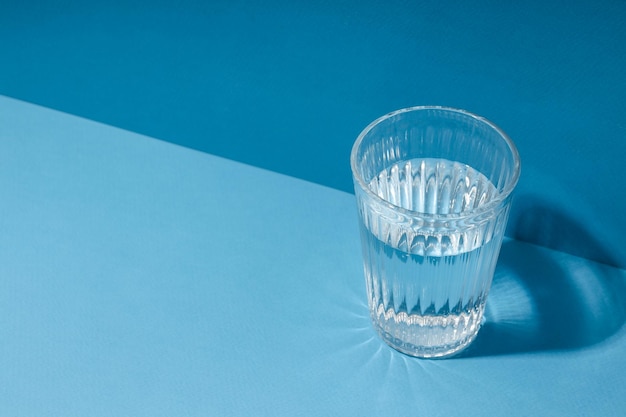 Glass of water on blue background space for text