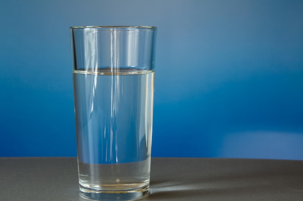 Glass of water is on the table blue background