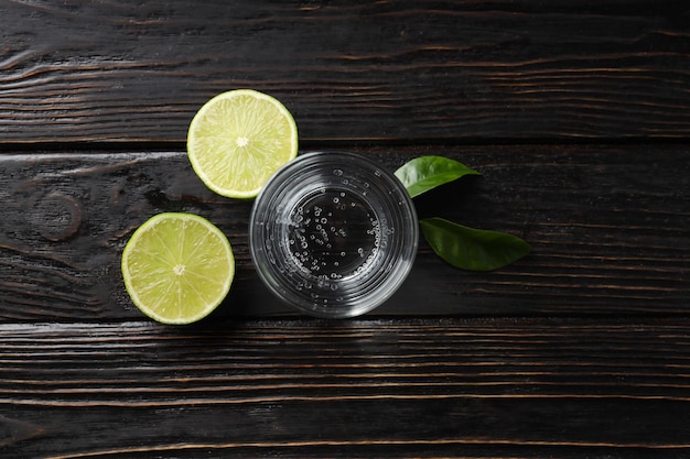 Glass of water lime and leaves on wooden background