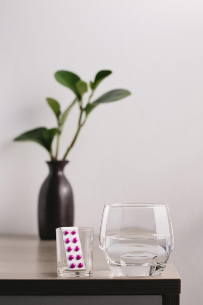 A glass of water and medicine on the wooden tablex9