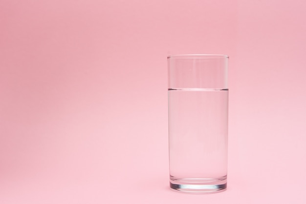 Glass of water on pink background