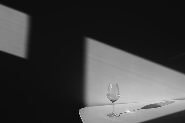 a glass of water on a white background with a shadow chiaroscuro from the window closeup copy space