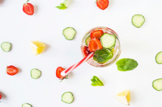 A glass of water with the addition of strawberries, cucumber, mint and lemon