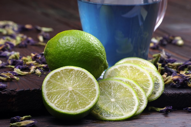 A glass of water with limes and a blue cup of water.