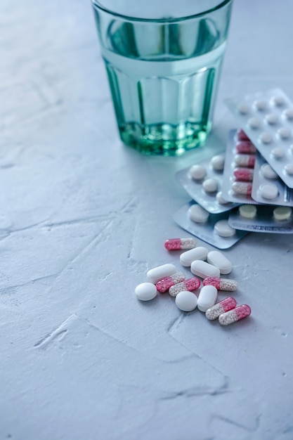 Glass Of Water With Pills And Tablets On The Gray surface.