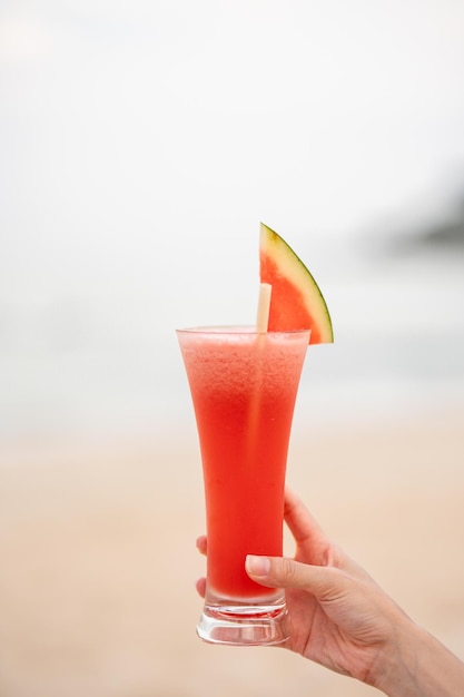 Glass of watermelon juice with blur ocean background.