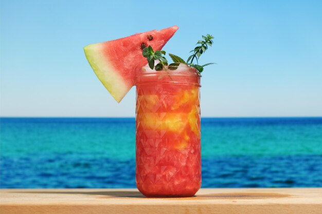 Glass of watermelon smoothie blue sea on background