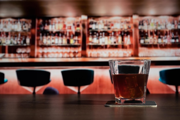 Glass of whiskey on the bar in front of the blur image bar