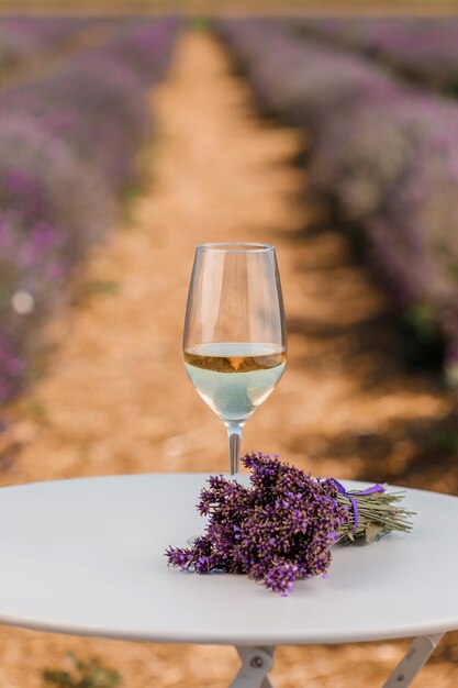 Glass of white wine in a lavender field in Provance Violet flowers on the background