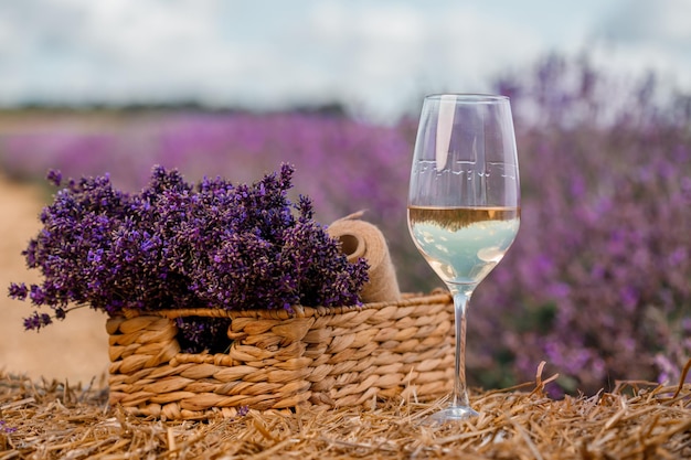 Glass of white wine in a lavender field in Provance Violet flowers on the background