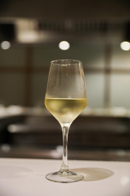 A glass of white wine sits on a table in a restaurant.