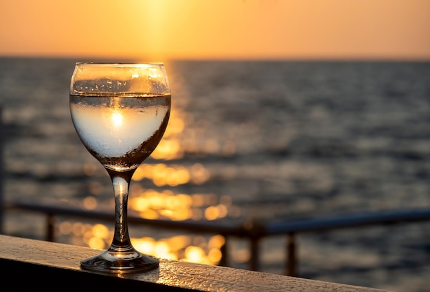 Glass of white wine at sunset near seaside with copy space