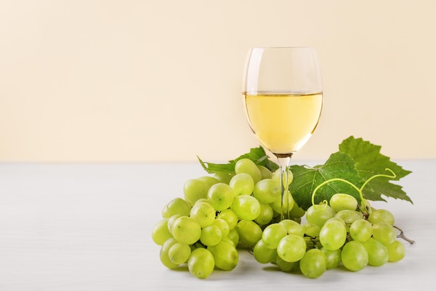 Glass of white wine and white grape on wooden table Wine composition with copy space for design