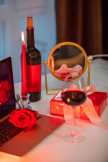 Glass of wine with gift box in front of laptop online dating