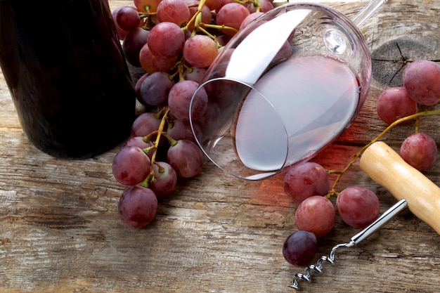 Glass of wine with grapes on wooden table