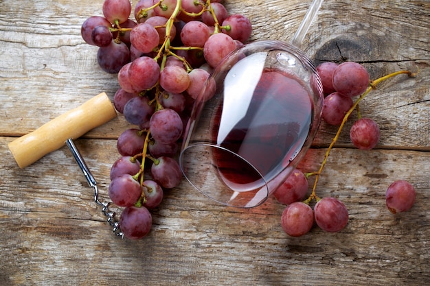 Glass of wine with grapes on wooden table