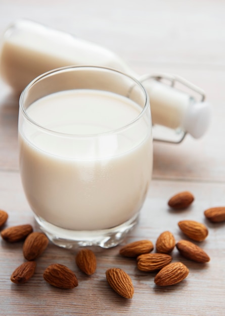 Glass with almond milk and almonds on the table