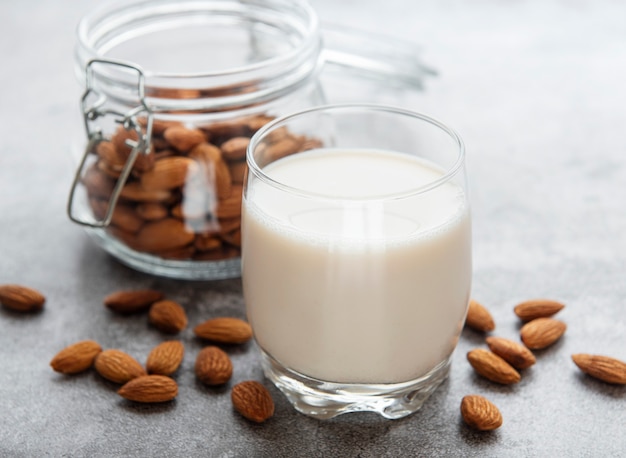 Glass with almond milk and almonds on the table