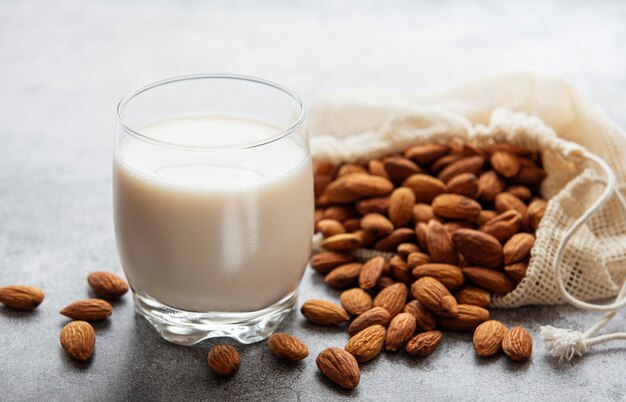 Glass with almond milk and almonds on the table