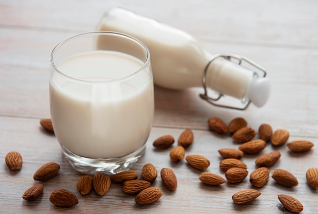 Glass with almond milk and almonds on the table