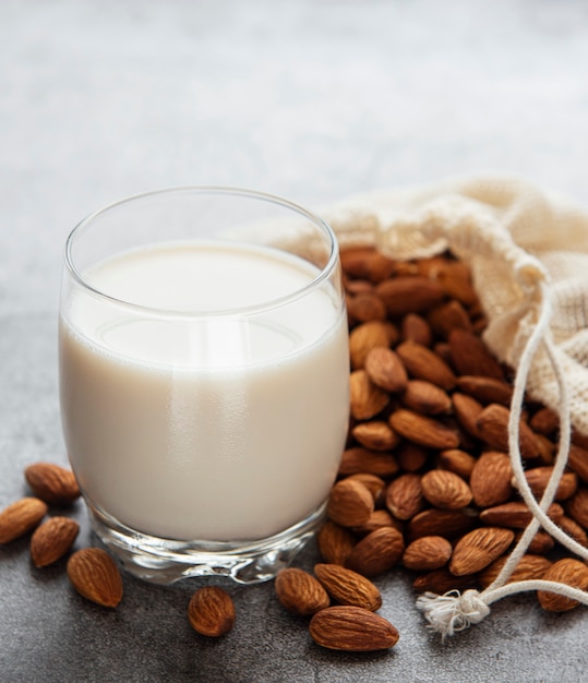 Glass with almond milk and almonds on the table