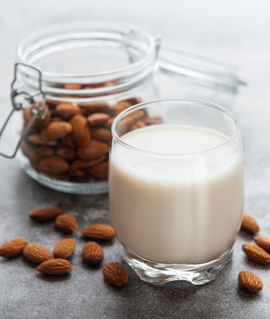 Glass with almond milk and almonds on the table