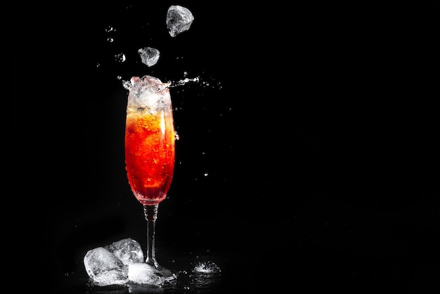 Glass with aperol cocktail on black background ice falls into the glass with the alcoholic beverage