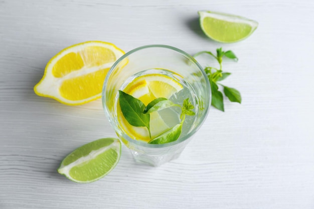 Glass with basil water and fruits on table