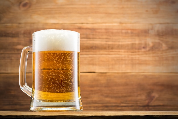 Glass with beer and chips on wooden wall.