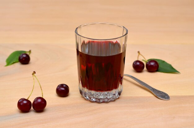 Glass with berry wine and cherries on the table