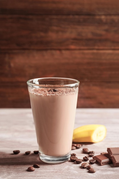 Glass with chocolate protein shake on wooden table