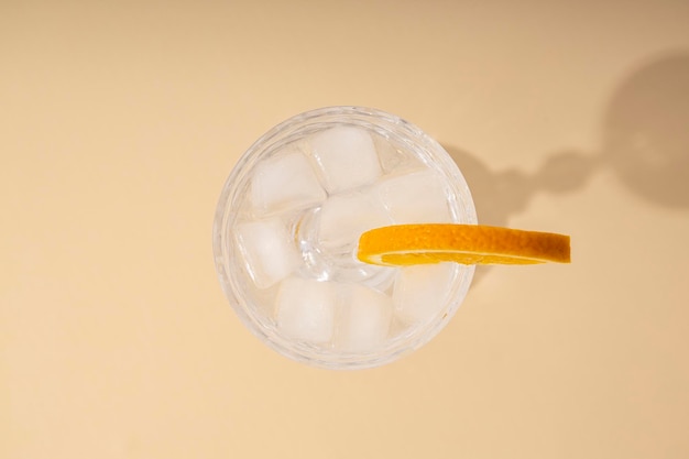 Glass with a cocktail with an orange slice on a beige background Top view flat lay