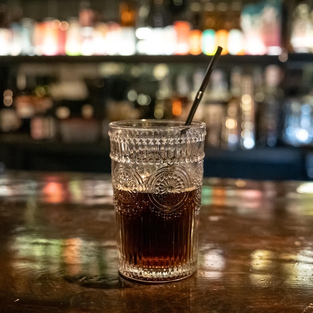 glass with dark alcoholic drink on table with blurred background