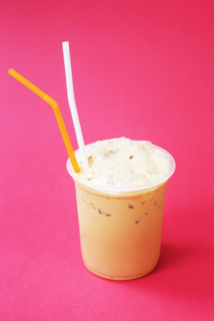 A glass with frappuccino coffee cocktail, cold refreshing drink or beverage with ice on red background