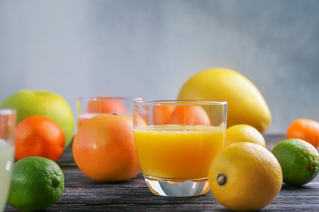 Glass with fresh citrus juice and fruits on table