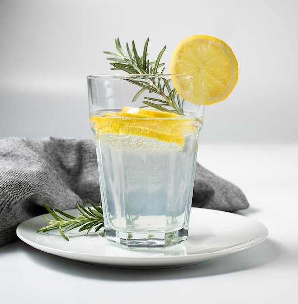 Glass with fresh lemon water or homemade lemonade and rosemary