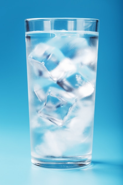 A glass with ice and clean water on blue