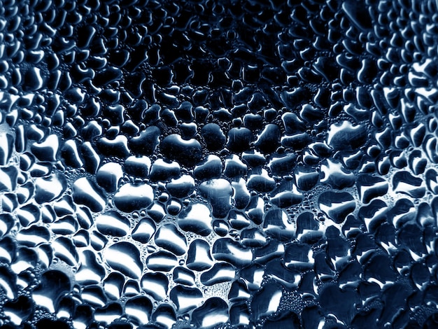 Glass with raindrops on blue tone background