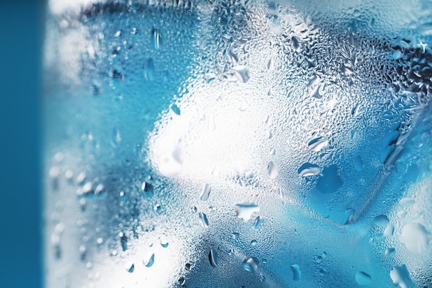 Glass with water and ice cubes on a blue background