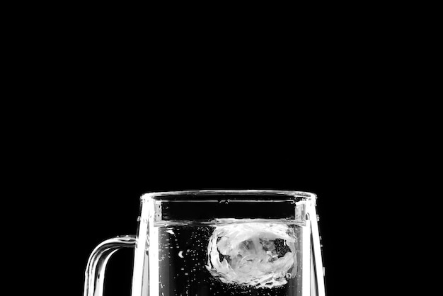 Glass with water ice and splashes on a black background