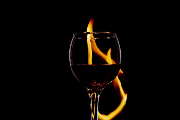 Glass with wine on fire and flame on a black background insulation